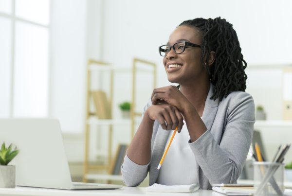 Smiling Black Business Lady Sitting At Laptop At Workplace