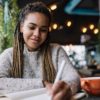 Talented female author writing ideas to education textbook spending leisure weekend in cafeteria